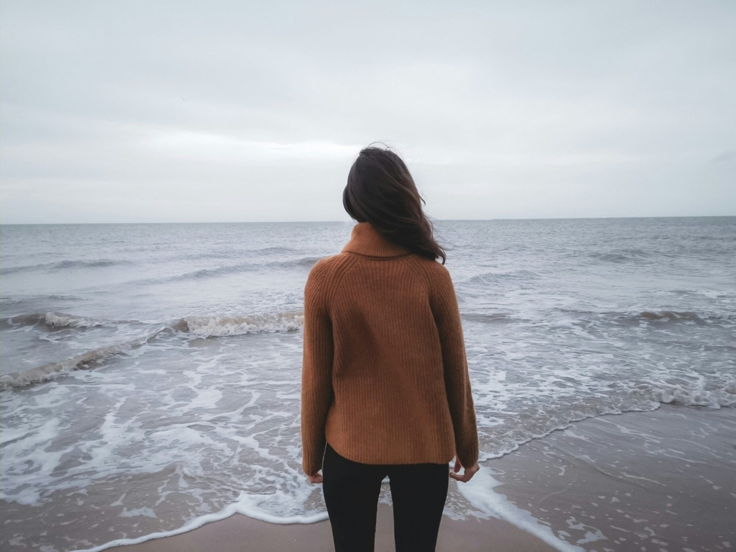 Woman managing anxiety with holistic tools by the ocean
